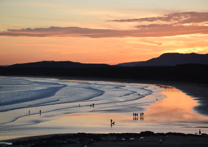 People walking along Seven Mile Beach during twilight in Gerroa, NSW, Australia