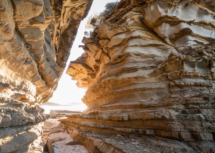 Sun shining through a sandstone passage at Wasps Head in Murramarang National Park