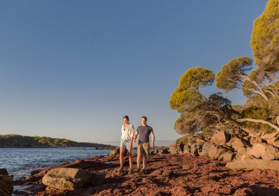 Couple walking through Bittangabee Bay on the Light to Light Walk in the Sapphire Coast